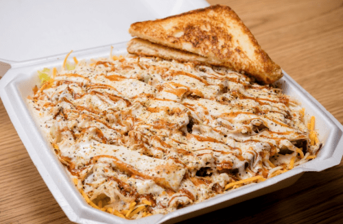 A takeout container filled with shredded chicken, cheese, and sauce, accompanied by a slice of toasted bread.