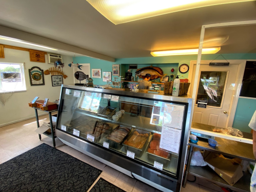 A seafood market interior featuring a glass display case filled with various fish and seafood products.