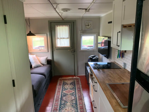 Cozy interior of a small home featuring a kitchen, living area with a sofa, and a decorative rug.