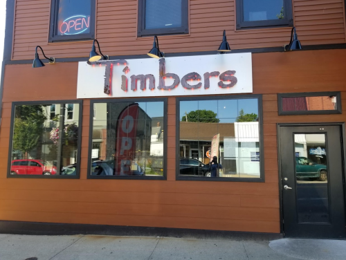 Exterior of a restaurant named "Timbers," featuring large windows and an "Open" sign.