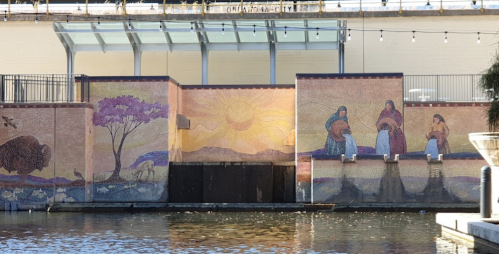 Colorful mural depicting nature and figures by a water feature, with a sunny backdrop and vibrant scenes.
