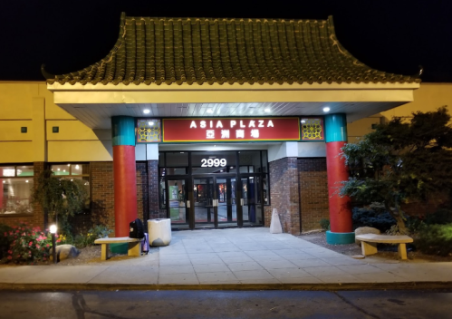 Entrance of Asia Plaza at night, featuring a traditional Asian-style roof and colorful columns.