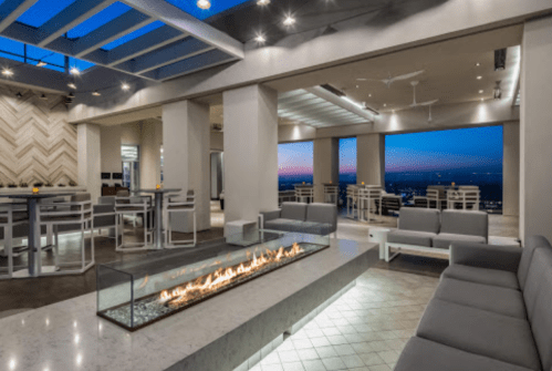 Modern rooftop lounge with a fire pit, sleek furniture, and panoramic views of the sunset.