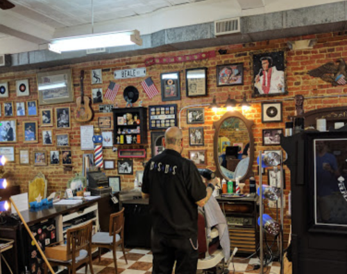 A barber shop with vintage decor, including photos, guitars, and memorabilia, featuring a barber attending to a customer.
