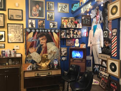 A vibrant room filled with Elvis memorabilia, photos, and vintage decor, featuring a barber shop theme and two black chairs.