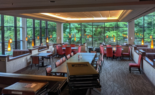 A spacious restaurant interior with large windows, modern lighting, and tables set for dining.