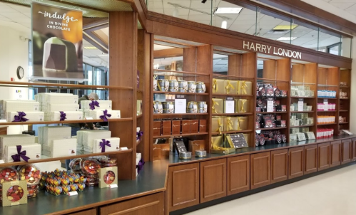 A display of Harry London chocolates featuring various packaged treats and a promotional poster in a store setting.