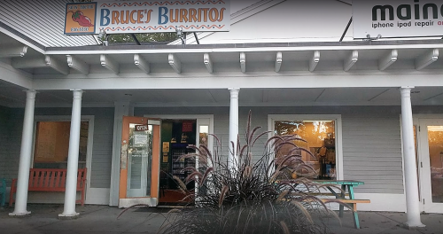 Exterior of Bruce's Burritos, featuring a colorful sign, entrance, and a plant in the foreground.
