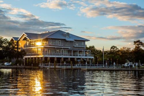 A waterfront building reflecting sunlight at sunset, surrounded by trees and a calm water surface.