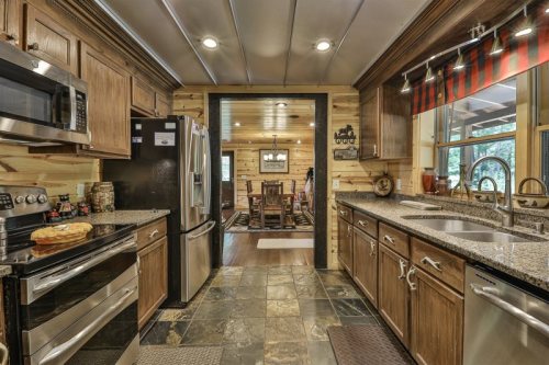 A modern kitchen with wooden cabinets, stainless steel appliances, and a view into a cozy dining area.