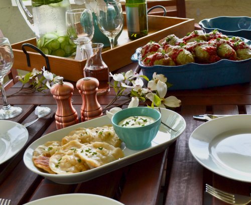 A beautifully set table featuring plates of pasta, a bowl of sauce, and a dish of meatballs, with decorative flowers.