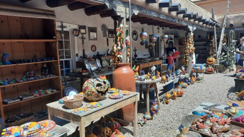 A vibrant outdoor market filled with colorful crafts, pottery, and decorations, showcasing a festive atmosphere.