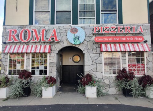 Exterior of Roma Pizzeria featuring stone walls, red and white striped awnings, and a sign for Connecticut-style pizza.