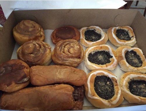A box of assorted pastries, including cinnamon rolls, poppy seed rolls, and glazed donuts.