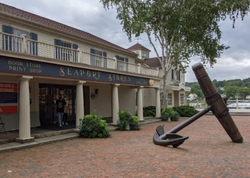 A quaint storefront labeled "Seaport Stores" with an anchor sculpture in front and trees nearby.