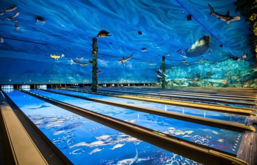 Bowling alley with a vibrant underwater-themed ceiling and lanes featuring oceanic designs and marine life.