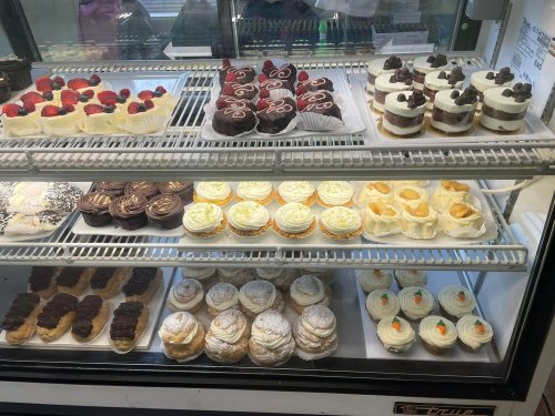 A display case filled with various desserts, including cupcakes, pastries, and chocolate treats.