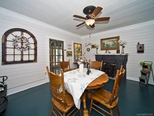 Cozy dining area with a wooden table, chairs, and a decorative fireplace, featuring white walls and blue flooring.
