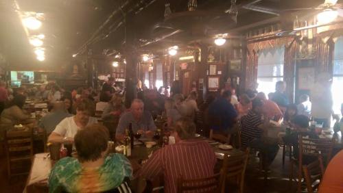 A busy restaurant filled with diners at tables, enjoying meals in a lively atmosphere.