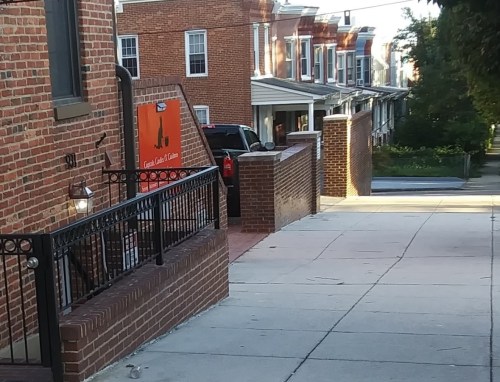 A brick sidewalk leads to a building with a sign for "Great Coffee & Tea," surrounded by residential houses.