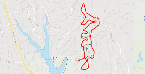 Map showing a winding red trail through a hilly landscape, with a lake and roads nearby.