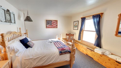 Cozy bedroom with a wooden bed, American flag decor, and natural light from a window.