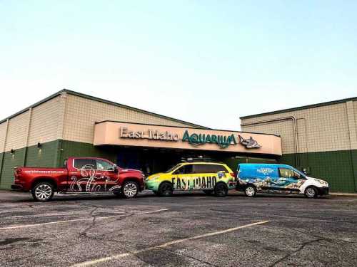 Three vehicles parked in front of East Idaho Aquarium, showcasing colorful branding and logos.