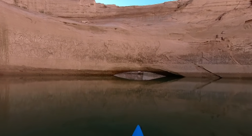 A serene view of a canyon wall reflected in calm water, with a blue kayak in the foreground.