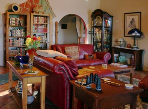 Cozy living room with a red leather sofa, bookshelves, decorative items, and a warm, inviting atmosphere.