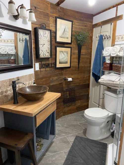 A cozy bathroom featuring wooden accents, a vessel sink, framed art, and a glass shower.