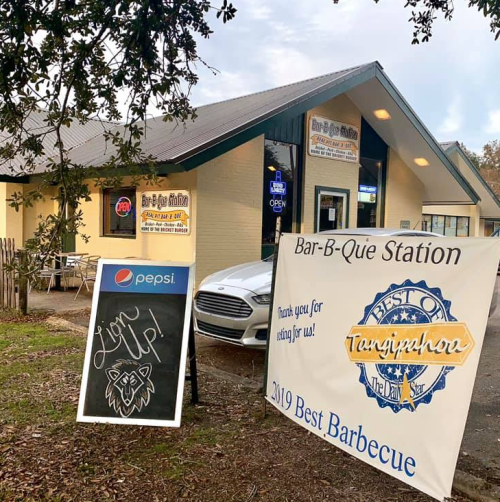 A barbecue restaurant with a sign thanking customers and a chalkboard advertising Pepsi outside.