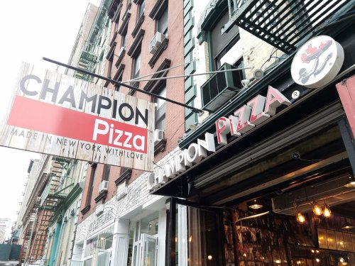 Sign for Champion Pizza in New York, featuring a red and white design with the tagline "Made in New York with love."