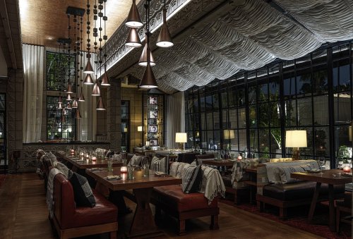 Cozy restaurant interior at night, featuring wooden tables, warm lighting, and stylish decor with hanging lamps.
