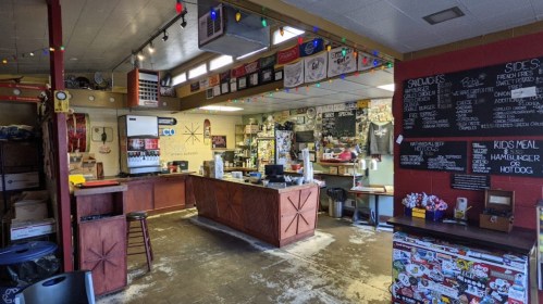 A cozy diner interior with a counter, seating, and walls decorated with posters and stickers.