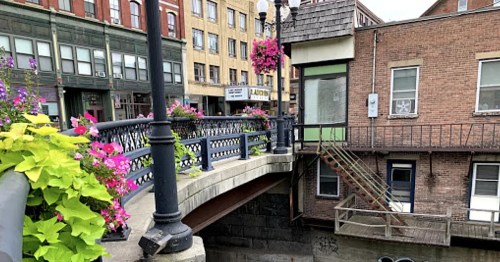 A charming bridge adorned with colorful flowers, connecting buildings in a quaint urban setting.