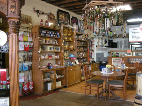 A cozy shop interior with wooden shelves filled with crafts, a table, and an ice cream parlor sign in the background.