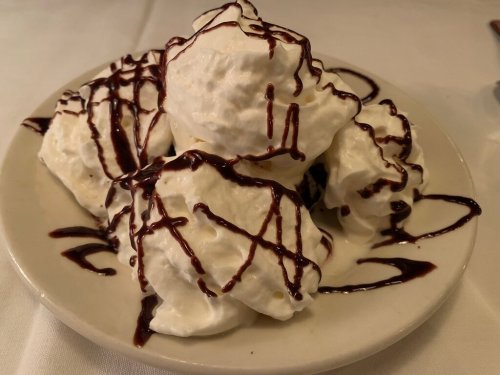 A plate of fluffy whipped cream topped with chocolate drizzle, arranged in a mound.