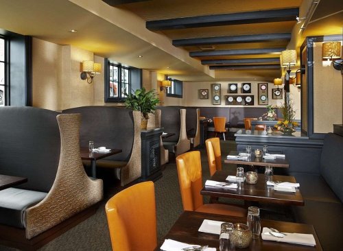 Cozy restaurant interior with booths, tables, and warm lighting, featuring a modern design and decorative wall art.
