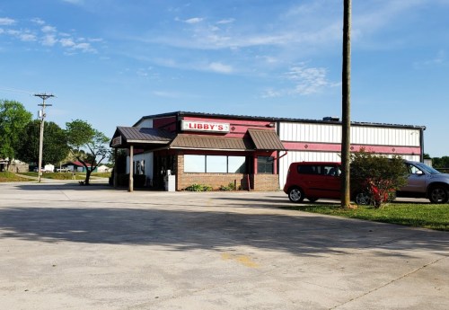 A restaurant named Libby's with a red and white exterior, parked cars, and a clear blue sky in the background.