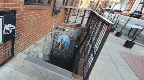 A staircase leading down to a brick-walled entrance, with a decorative archway at the bottom.