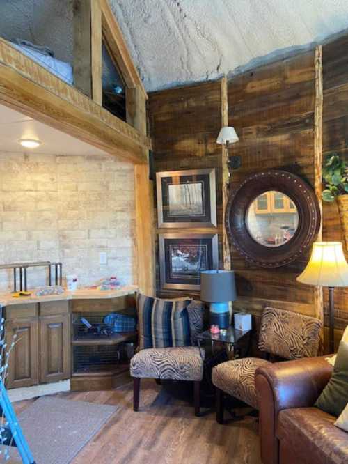 Cozy interior of a rustic cabin with wooden walls, a seating area, and decorative elements like a mirror and lamp.