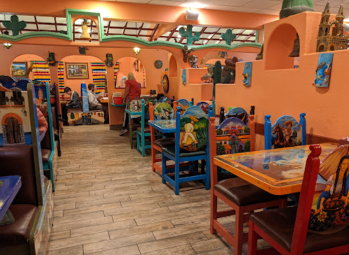 Colorful restaurant interior with vibrant artwork, wooden tables, and chairs, creating a lively atmosphere.