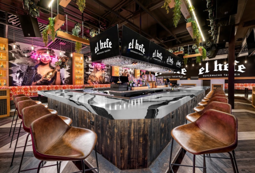 A modern bar with a striking marble countertop, surrounded by stylish seating and vibrant wall art.