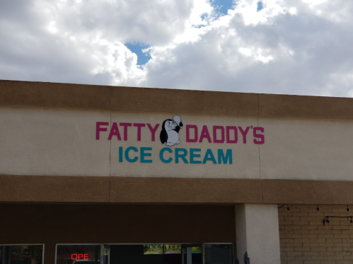Sign for "Fatty Daddy's Ice Cream" with a cartoon character holding an ice cream cone, under a cloudy sky.