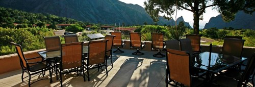 A patio with tables and chairs overlooking a scenic mountain landscape in the background.