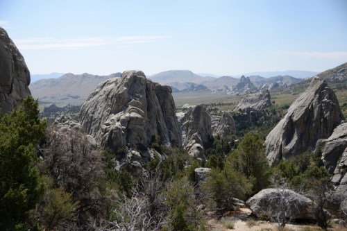 A panoramic view of rugged rock formations and distant mountains under a clear blue sky.