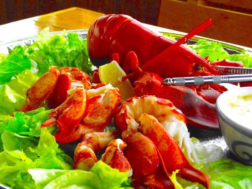 A vibrant platter featuring a cooked lobster on a bed of lettuce, with lemon wedges and seafood dipping sauce.