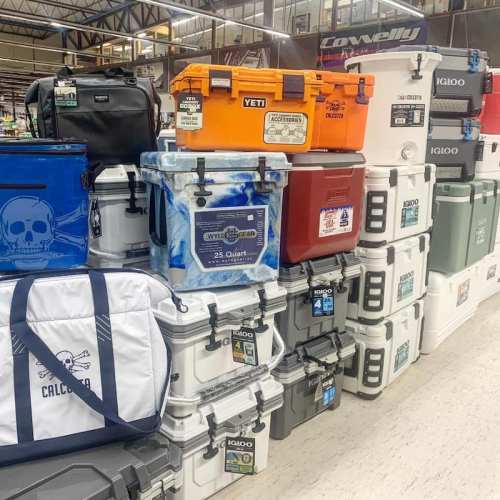 A display of various coolers and ice chests in different colors and sizes stacked in a store.