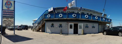 Exterior view of Champlin's Seafood Market and Restaurant, featuring flags, a sign, and a clear blue sky.