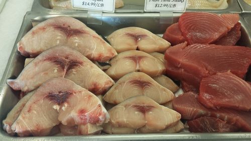 Fresh fish display featuring swordfish steaks and tuna, priced per pound.